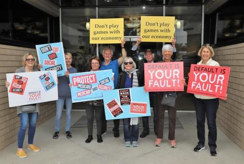  Indivisibles and ​​the Central Orange County Democratic Club hold rally signs outside of Republican Rep. Young Kim’s (CA-40) office